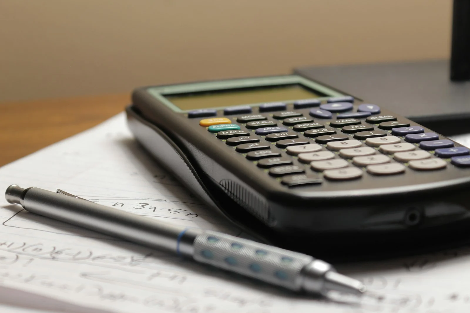 Calculator and pen on a page of handwritten figures